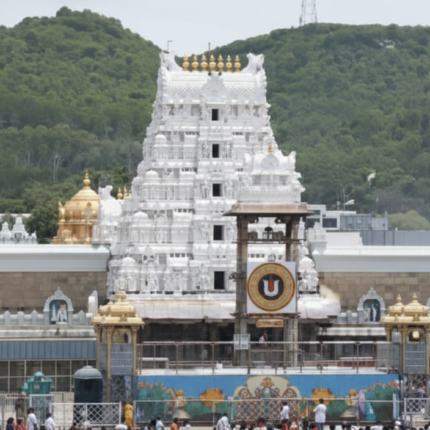 "The iconic white gopuram of the Sri Venkateswara Temple (Tirupati Balaji) at Tirumala, with devotees gathered in the foreground and lush green hills of the Eastern Ghats behind."